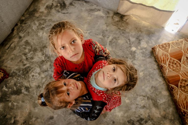 Three children in Idlib, Syria look up, showcasing innocence and unity.