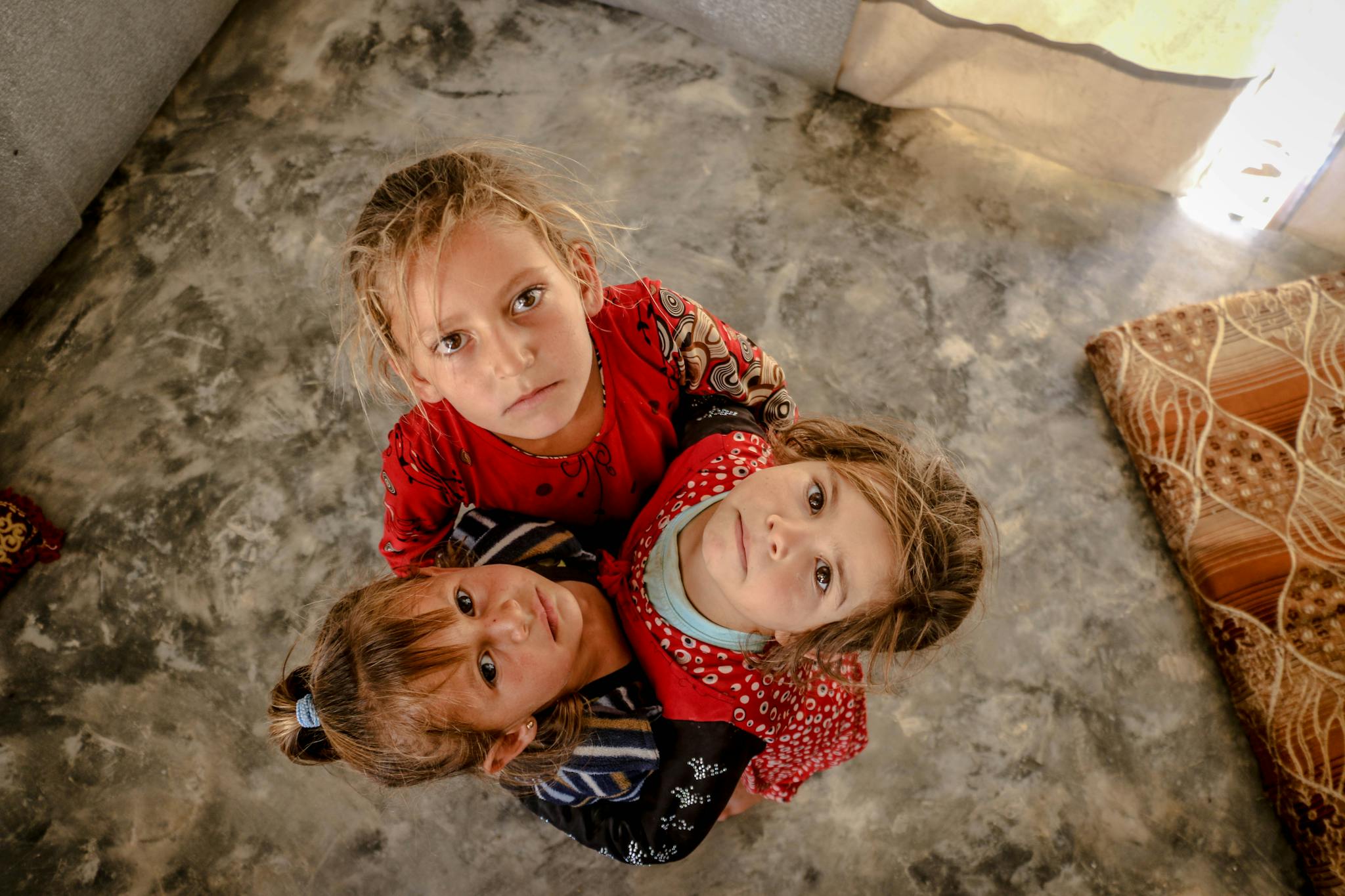 Three children in Idlib, Syria look up, showcasing innocence and unity.